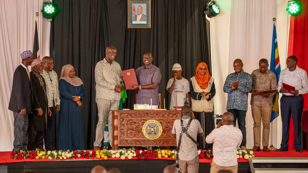 El presidente William Ruto, junto a integrantes de la comunidad pemba y funcionariado gubernamental, que dan fe de la firma del documento oficial que reconoce la ciudadanía keniana del pueblo pemba. © ACNUR/Charity Nzomo