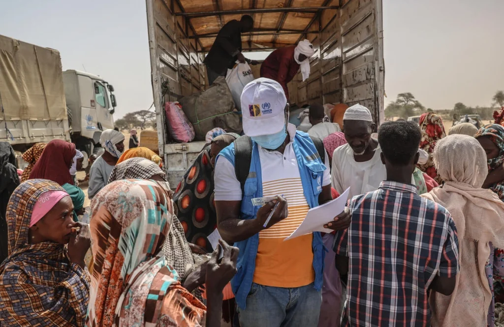 Un miembro del equipo de ACNUR revisa la documentación de las personas refugiadas recién llegadas de la región sudanesa de Darfur del Norte, en un centro de tránsito junto al cruce fronterizo de Tine, en Chad. © ACNUR/Caitlin Kelly