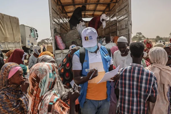Un miembro del equipo de ACNUR revisa la documentación de las personas refugiadas recién llegadas de la región sudanesa de Darfur del Norte, en un centro de tránsito junto al cruce fronterizo de Tine, en Chad. © ACNUR/Caitlin Kelly