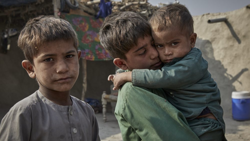 Hamdullah, de 8 años, sostiene a su hermano Sulaiman, de 2, quien se siente mal, en su hogar temporal en Jalalabad.