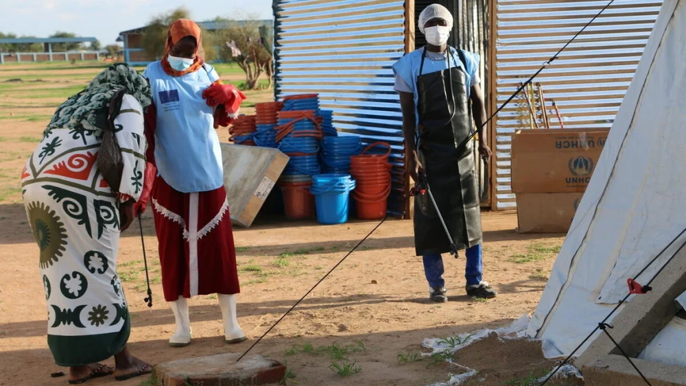 Trabajadores sanitarios en el asentamiento de refugiados de Dougui, en el este de Chad, desinfectan locales e instalaciones de kits de lavado de manos para limitar la cadena de contaminación por cólera. © ACNUR/Bockarie Kallon