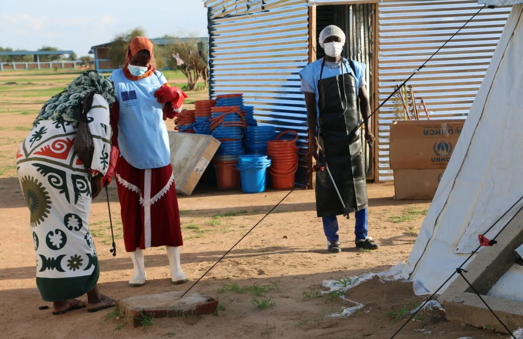 Trabajadores sanitarios en el asentamiento de refugiados de Dougui, en el este de Chad, desinfectan locales e instalaciones de kits de lavado de manos para limitar la cadena de contaminación por cólera. © ACNUR/Bockarie Kallon