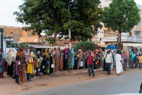 Familias desplazadas recientemente de El Fasher hacen fila en un reparto de alimentos, junto a residentes de larga duración, en Omdurman, la segunda mayor ciudad de Sudán. © ACNUR/Ala Kheir