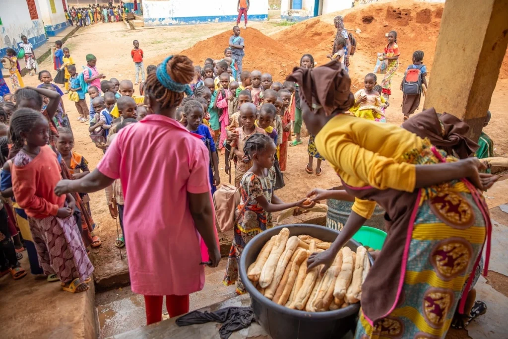 El personal del comedor distribuye el almuerzo a estudiantes de la escuela primaria de Gado-Badzéré.© ACNUR/Charity Nzomo