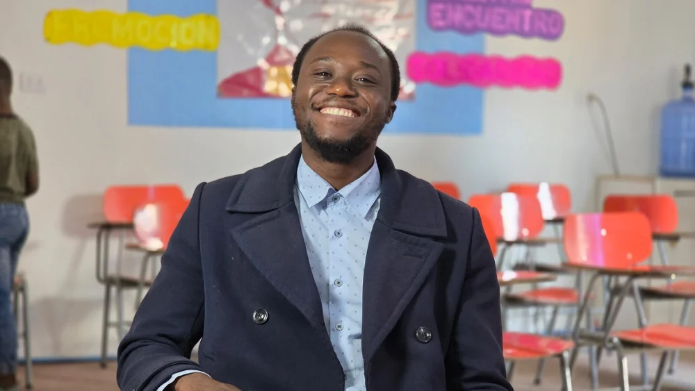 Ralph Jean Baptiste sonríe en la sala de clases, donde cada palabra se convierte en un puente de integración y esperanza para su comunidad haitiana en Chile. © ACNUR/Stephanie Rabi