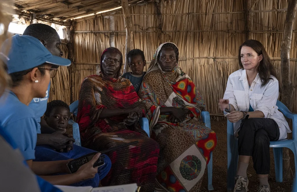Kristin Davis (a la derecha), Embajadora de Buena Voluntad de ACNUR, escucha al personal de la Agencia mientras traduce el relato de Ayuen y Christina, refugiadas sursudanesas retornadas, que explicaron las dificultades de su viaje durante una visita al centro de recepción de Wunthou, en el condado de Renk, en el Estado del Alto Nilo, Sudán del Sur. © ACNUR/Etinosa Yvonne
