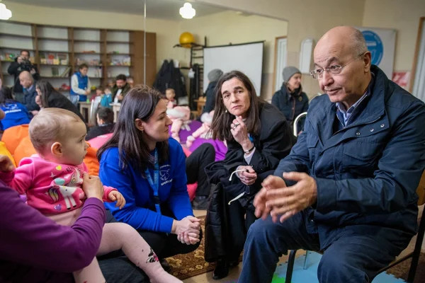 El Alto Comisionado de la ONU para los Refugiados, Barham Salih (a la derecha), habla con Nina (a la izquierda) en un centro de tránsito en Zaporizhzhia, al sureste de Ucrania, después de que ella fuera evacuada de su casa dañada por las bombas junto con su hija y sus tres nietos. © ACNUR/Nikola Ivanovski