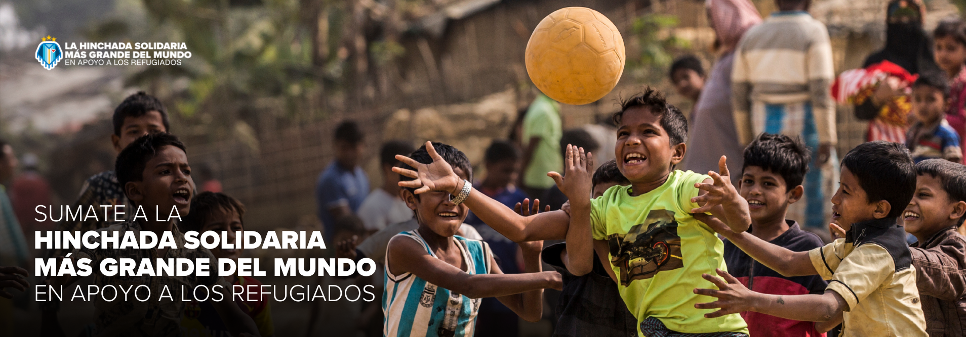 Children playing soccer in a crowded outdoor scene, part of a refugee-support charity banner with a logo in the corner.