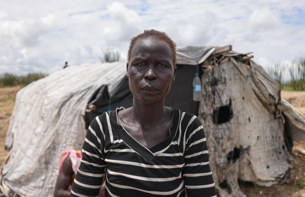 Aduot Wuoi Monjuon, desplazada interna, posa junto a su refugio en Bor, Sudán del Sur, donde se ha desplazado después de que las inundaciones la obligaran a huir de su aldea en el Estado de Jonglei, junto a su familia. © ACNUR/Tiksa Negeri