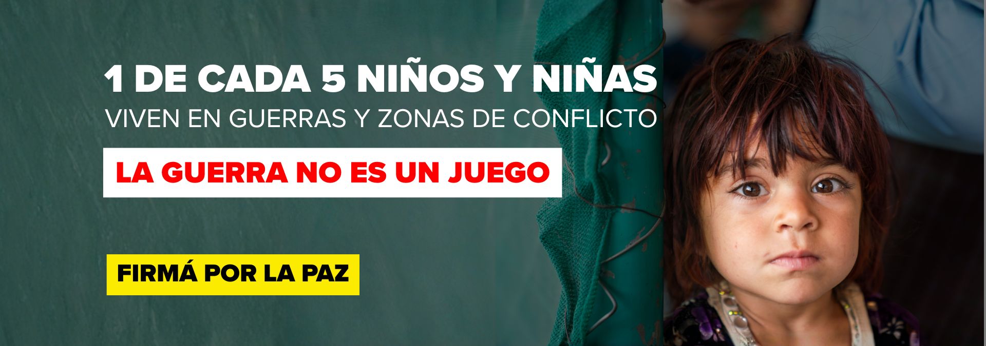 Young girl peeks from the right beside a bold Spanish anti-war banner reading 'LA GUERRA NO ES UN JUEGO' and 'FIRMA POR LA PAZ'.