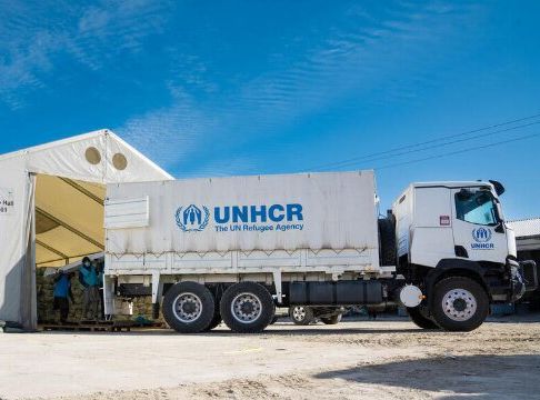 Un camión de ACNUR descarga ayuda humanitaria frente a un depósito